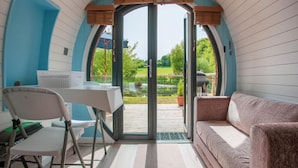 An arched room with a table and chairs, a sofa, and a view of a garden through a glass door.