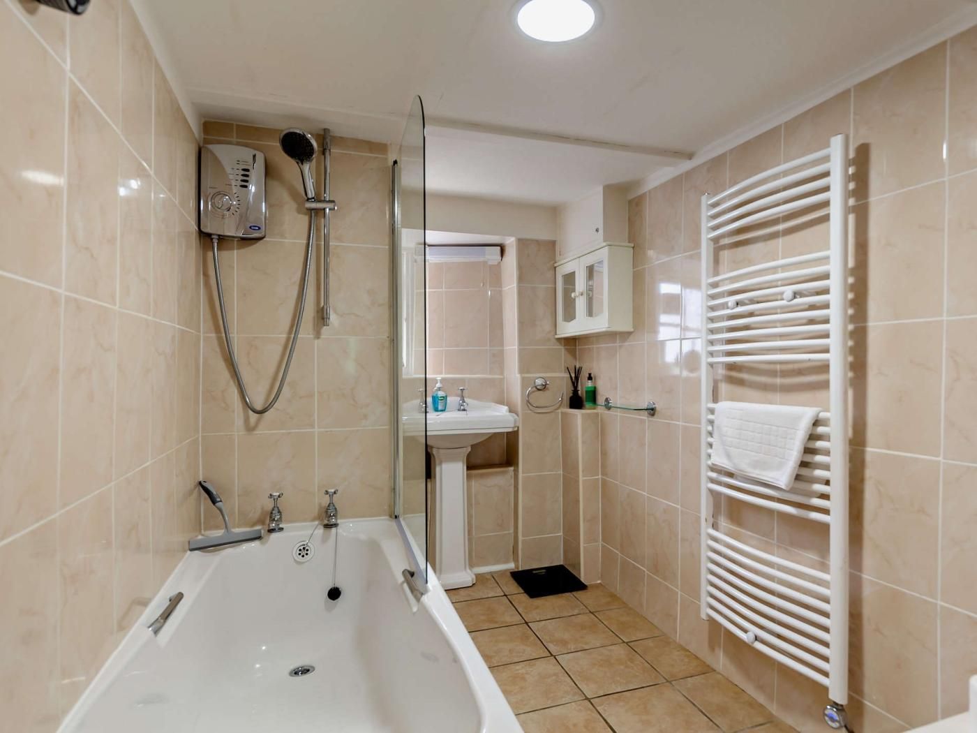 Un bagno moderno con vasca, doccia e termosifone bianco.