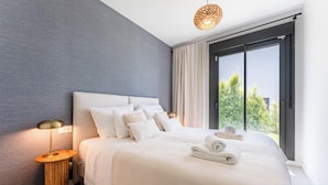 Een moderne hotelkamer met een groot bed, een bedlampje en uitzicht op groen.