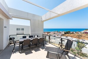 Een balkon met een tafel en stoelen, met uitzicht op een kustplaatsje.