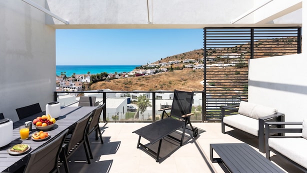 Een balkon met een ontbijttafel, een stoel en een bank.