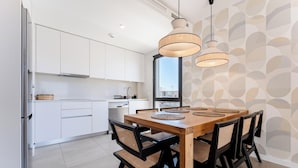 Een moderne keuken met witte kasten, een houten eettafel met geweven placemats en hanglampen.