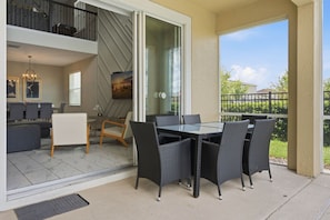An outdoor patio with a dining table and chairs, a sofa, and a staircase leading to an upper level. - 5BR ChampionsGate Home w/ Pool & Theme Rooms (Kissimmee)