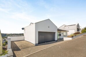 Ein modernes Wohngebäude mit Garage, Satellitenschüssel und Blick auf die Umgebung.