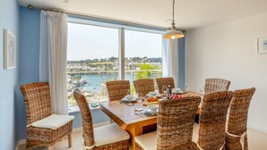 Ein Essbereich mit Korbstühlen und einem Holztisch, gedeckt für sechs Personen, mit Blick auf eine malerische Fluss- und Stadtlandschaft.