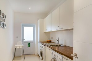 A compact kitchen with a washing machine, a sink, and a door with a window. - 5 Bed in Fowey (oc-77657) (Polruan)