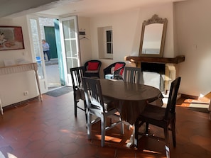 A dining area with a round table, chairs, a mirror, and a door leading outside.