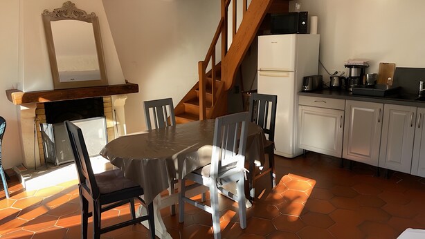 Ein Essbereich mit einem runden Tisch, Stühlen, einer Holztreppe, einer Küche mit Schränken und einer Mikrowelle.