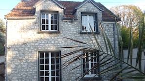 Ein Steinhaus mit zweistöckiger Struktur, einer Haustür und einer kleinen Terrasse mit Tisch und Stühlen.