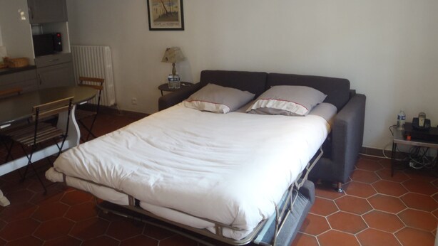 A bedroom with a bed, a desk, a chair, a lamp, and a picture on the wall.