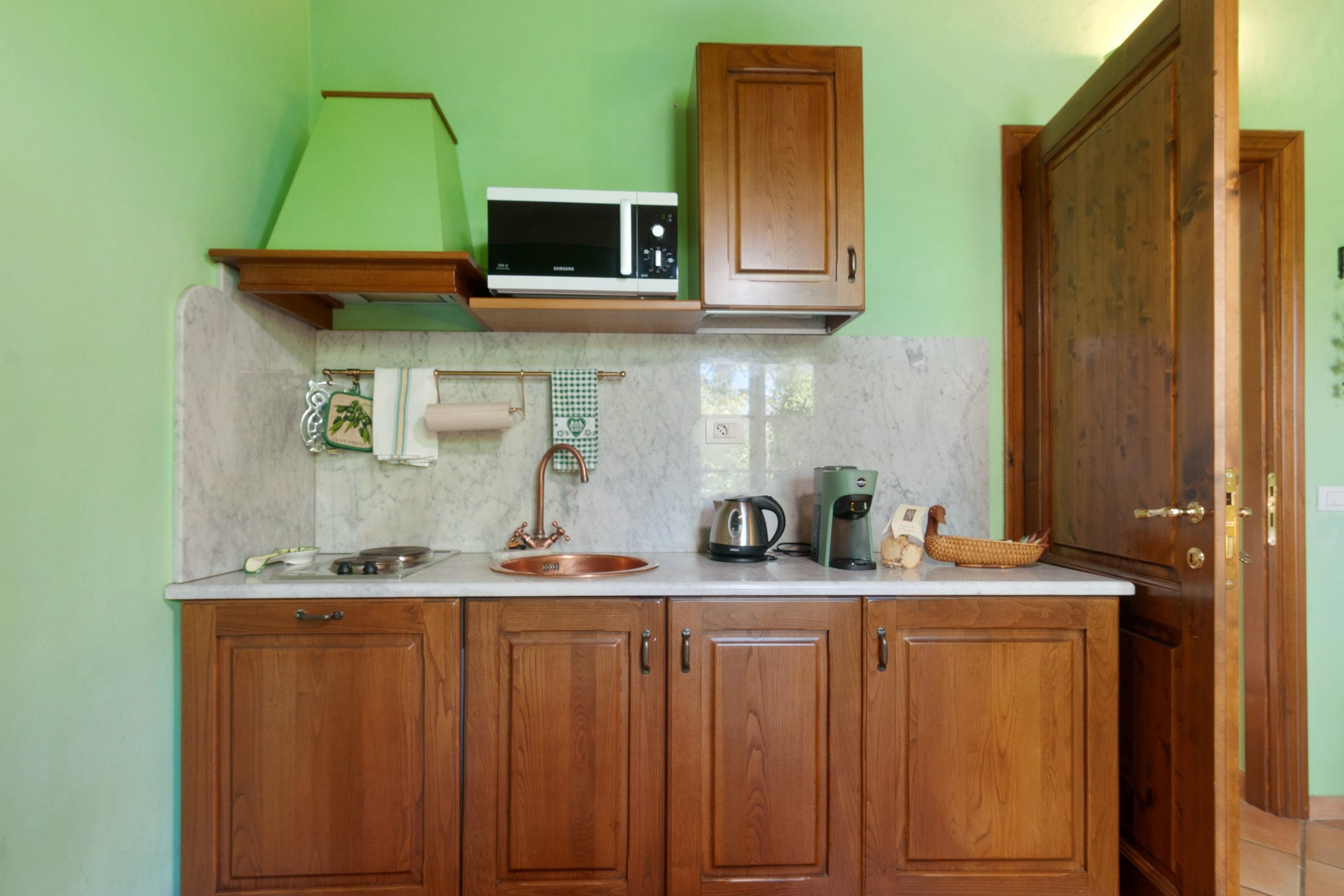 A kitchen with wooden cabinets, a microwave, a kettle, and a coffee maker.
