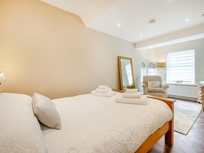 Ein Schlafzimmer mit einem großen Bett, einem Sessel, einem Spiegel und einer Heizung.