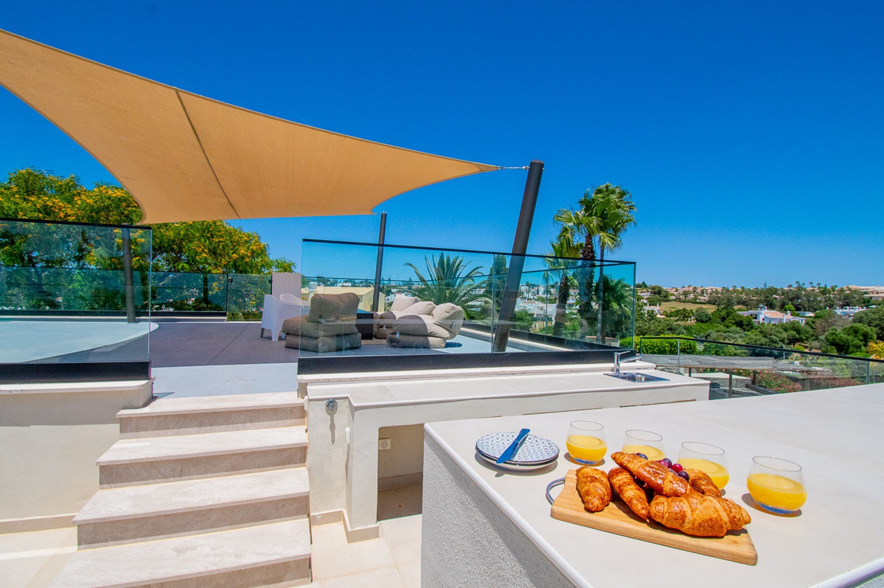 Una terraza en la azotea con una mesa dispuesta para el desayuno, asientos al aire libre y vistas al paisaje.