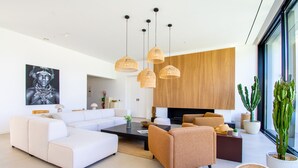 A modern living room with a white sofa, a brown armchair, a coffee table, and hanging wicker lamps. - Villa Cactus in Carvoeiro (Lagoa)