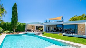 A modern house with a swimming pool, outdoor seating, and a large window overlooking the pool. - Villa Cactus in Carvoeiro (Lagoa)