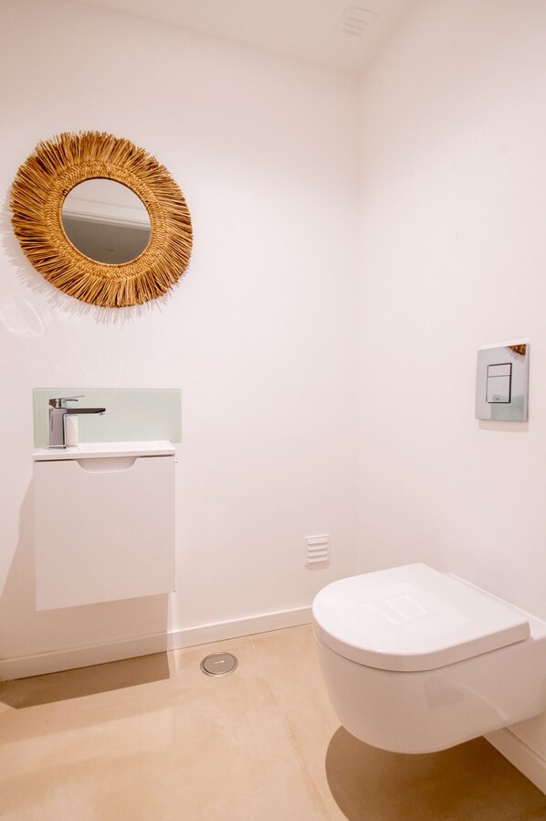 A bathroom with a toilet, a sink, and a mirror. - Villa Cactus in Carvoeiro (Lagoa)