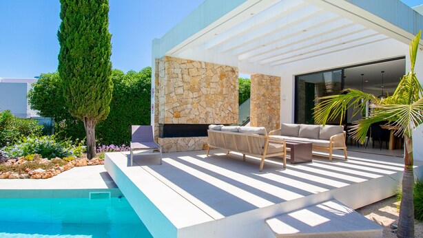 A modern outdoor living area with a pool, stone wall, and outdoor furniture. - Villa Cactus in Carvoeiro (Lagoa)