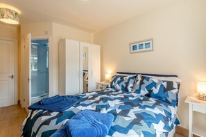 A bedroom with a bed, a wardrobe, a bathroom with a glass door, and a bedside table with a lamp. - 2 Bed in Bridlington (oc-77607) (Sewerby)