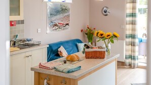 Een keuken met een aanrecht, een mand, een brood en een vaas met zonnebloemen.