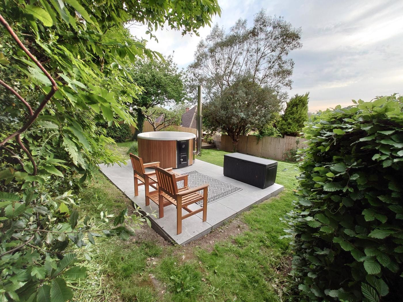 An outdoor patio with a hot tub, seating, and a small table.