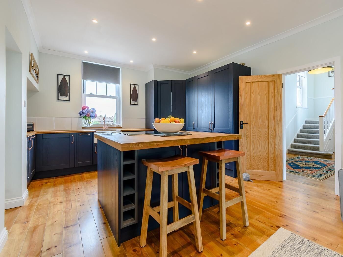 A modern kitchen with dark cabinets, a wooden island, and bar stools.