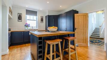 A modern kitchen with dark cabinets, a wooden island, and bar stools.