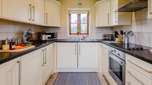 A kitchen with white cabinets, a black countertop, a stove, and a window with a view. - 2 Bed in Mold (oc-77603) (Pen-y-cefn)