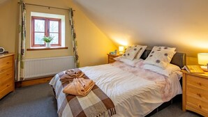 A bedroom with a bed, a window, a radiator, a bedside table, and a lamp. - 2 Bed in Mold (oc-77603) (Pen-y-cefn)