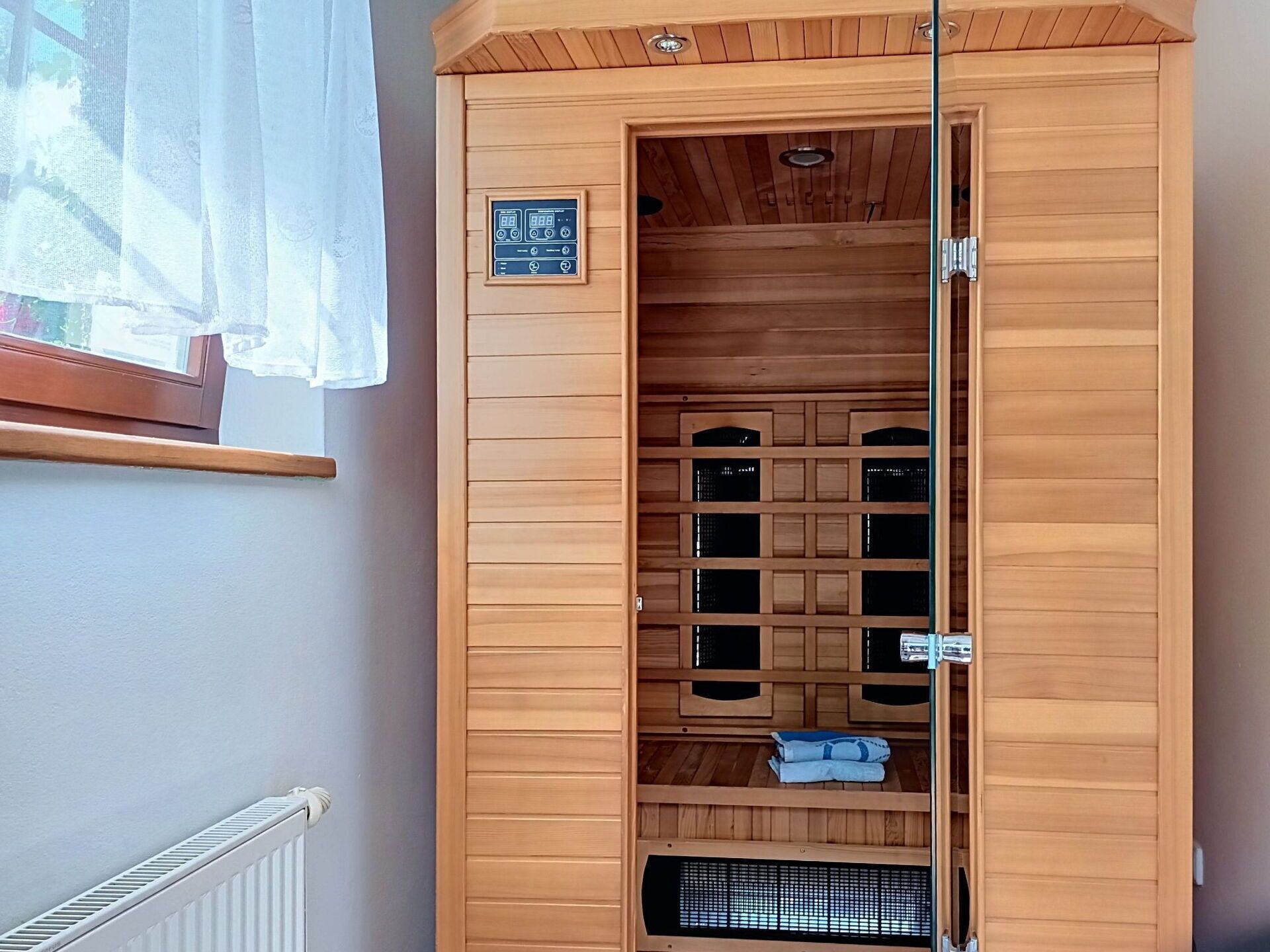 Una sauna con paredes de madera, un panel de control y una ventana con cortina.