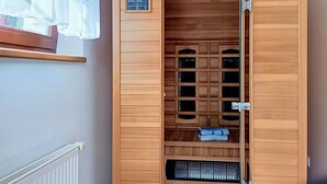 Een sauna met houten wanden, een bedieningspaneel en een raam met gordijn.