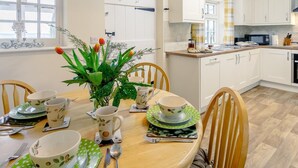 Ein Essbereich mit einem runden Tisch für vier Personen, umgeben von weißen Schränken, einer Mikrowelle und einer Kaffeemaschine.