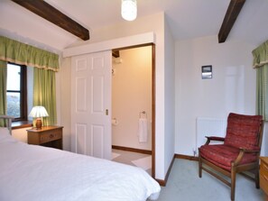 A bedroom with a bed, a chair, a nightstand, a door, and a radiator. - 2 Bed in Colwyn Bay (oc-77635) (Colwyn Bay)