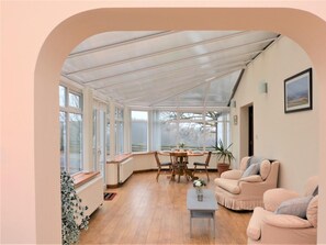 A conservatory with a dining table, chairs, and a sofa. - 2 Bed in Colwyn Bay (oc-77635) (Colwyn Bay)