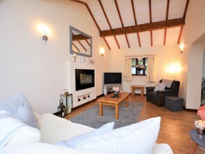 A living room with a TV, wooden beams, a fireplace, and a cozy seating area. - 2 Bed in Colwyn Bay (oc-77635) (Colwyn Bay)