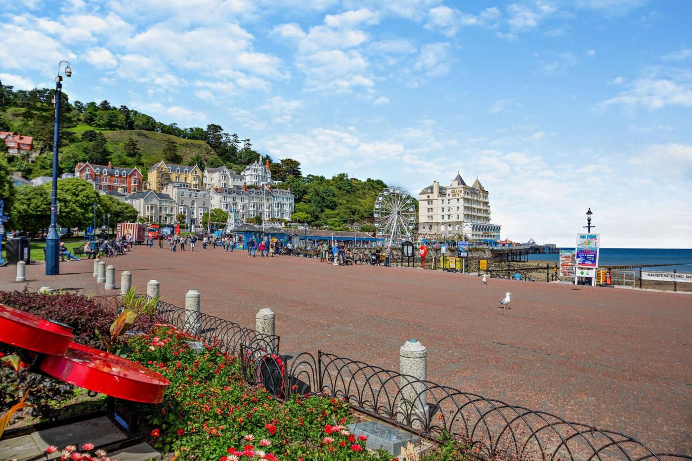 A seaside promenade with a Ferris wheel, a hotel, and a pier.