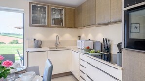 Uma cozinha moderna com forno embutido, pia e área de jantar com mesa posta para dois.