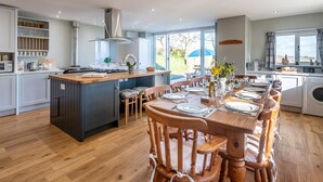 Een moderne keuken met een centraal eiland, een eethoek met houten stoelen en uitzicht op de omgeving.