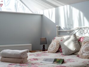 Ein Schlafzimmer mit einem Bett, Kissen, einer Lampe und einem Heizkörper.
