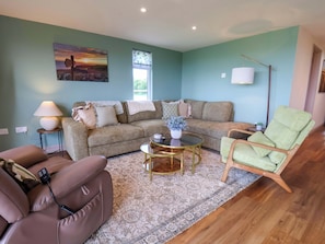 A living room with a sofa, a green armchair, a coffee table, and a lamp. - Freedom Lodge @ Summerfield Farm (Whitby)
