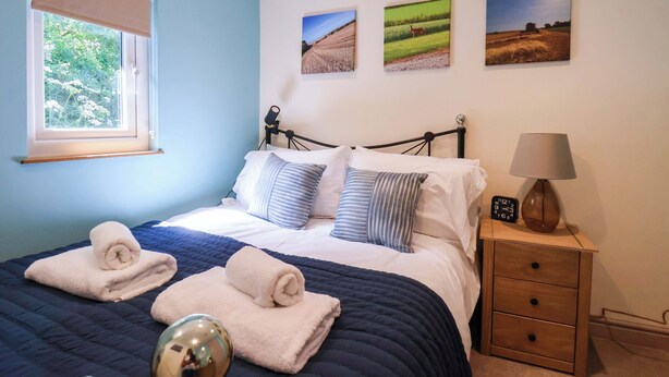 Ein Schlafzimmer mit einem Bett, einer Nachttischlampe, einem Nachttisch und drei Landschaftsbildern an der Wand.