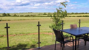 Eine Terrasse mit Tisch und Stühlen mit Blick auf ein saftiges Grasfeld.