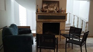 Una sala de estar con chimenea, un sofá y dos sillones.