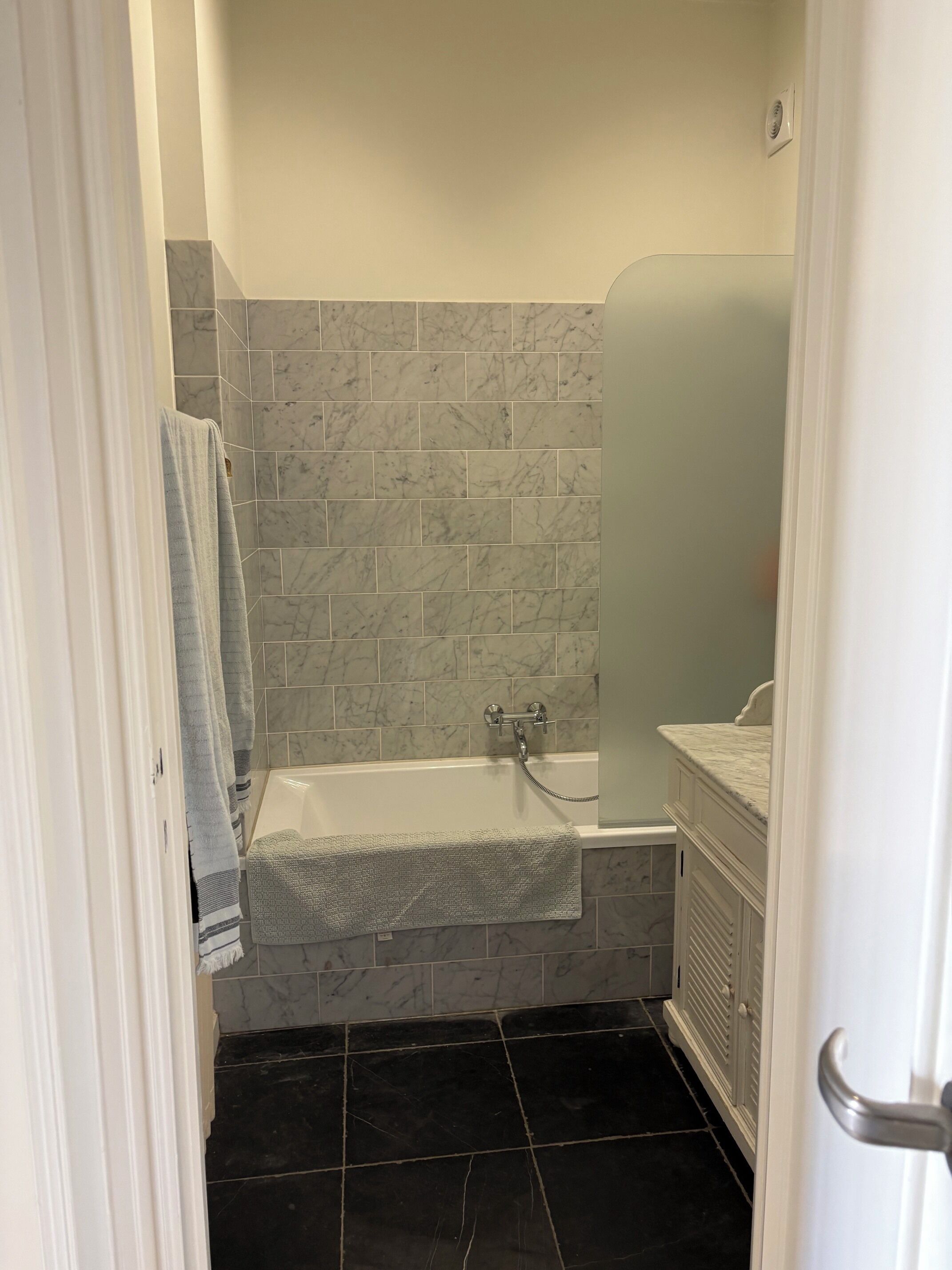 A bathroom with a bathtub, a sink, and a mirror.
