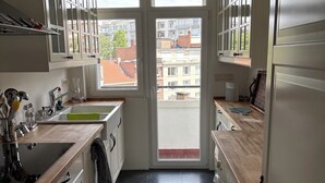 Une cuisine donnant sur la ville grâce à une porte-fenêtre, avec un évier, des placards et une cuisinière.