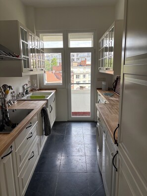 A kitchen with a view of the city through a door, a sink, cabinets, and a stove.