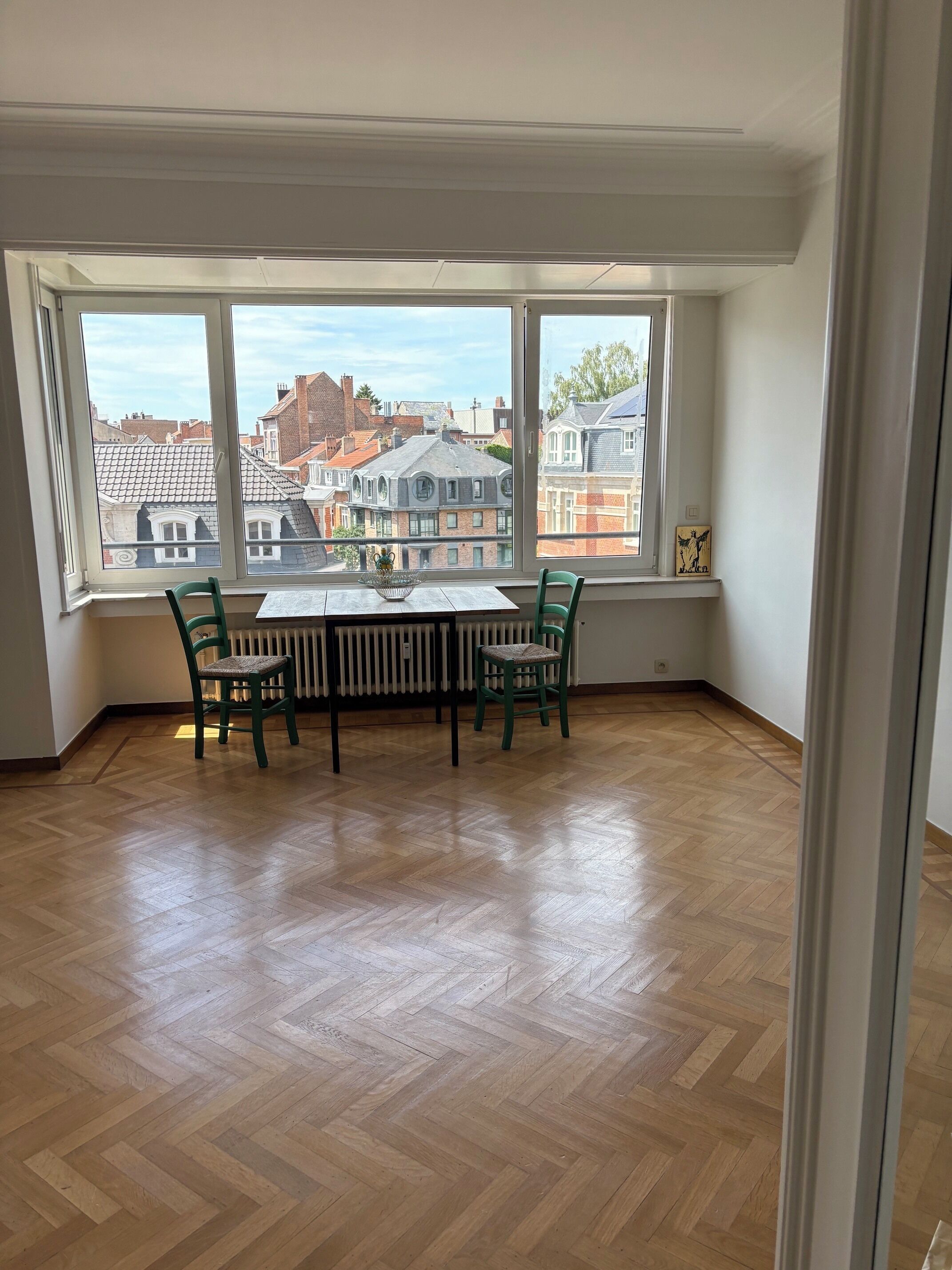 A room with a large window, a table with chairs, and a radiator.