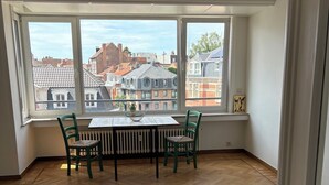 Een kamer met een groot raam, een tafel met stoelen en een radiator.