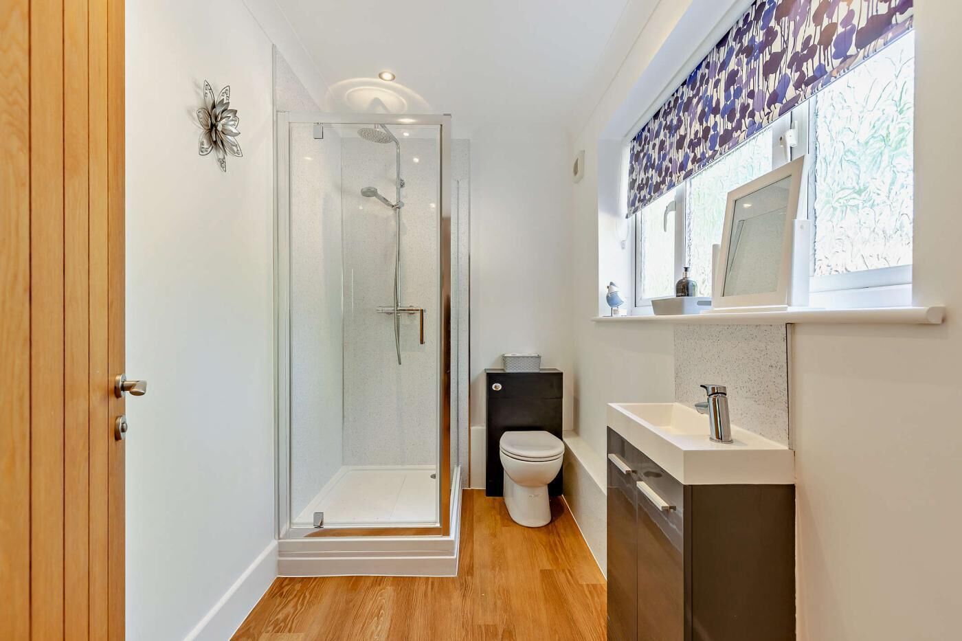 A modern bathroom with a glass shower enclosure, a toilet, and a sink with a mirror above it.