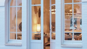 A building with a white facade, a large arched entrance, and a sign above the door. - Villa Les Mouettes, Cap Ferret (Lège-Cap-Ferret)