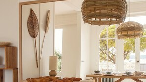 A room with a brick fireplace, a large mirror reflecting a dining area, and two woven light fixtures. - Villa Les Mouettes, Cap Ferret (Lège-Cap-Ferret)